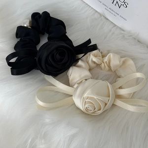 Detail of silk satin scrunchies with elegant rose flower and ribbon bow in cream and black