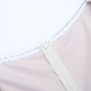 Detail of invisible zipper closure on pale pink mesh knit dress with silver sequins
