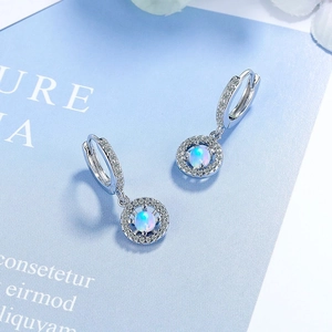 Elegant opal stud earrings with cubic zirconia halo in silver setting on blue background