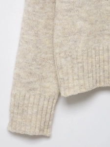 Close-up of rib-knit cuffs and hem on beige wool blend Christmas sweater