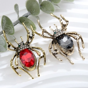 Detail of vintage spider brooches with red and grey oval gems and rhinestone accents