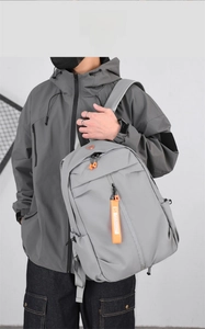 Close-up of grey large capacity laptop backpack with orange zipper details and side pockets