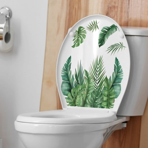 Close-up of tropical green leaves decals on a white toilet lid in a modern bathroom