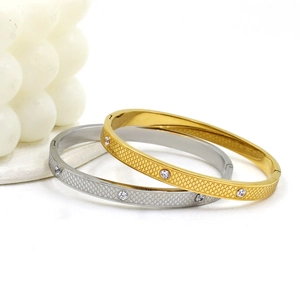 Detailed close-up of gold and silver steel bangles with fish scale texture and cubic zirconia
