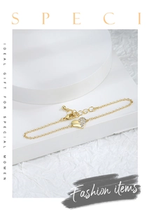 Detailed shot of gold-plated heart bracelet with sparkling cubic zirconia on white stands