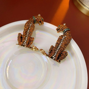 Detailed close-up of leopard head earrings with orange rhinestones and silver accents
