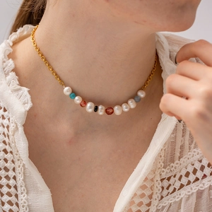 Détail d'un collier de perles et pierres colorées sur modèle avec chaîne dorée