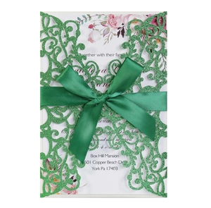 Detail of green glitter laser-cut wedding invitation with elegant silk ribbon bow