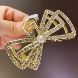 Détail d'une pince à cheveux papillon dorée avec strass brillants et perle élégante