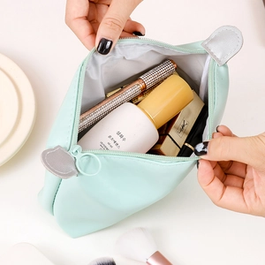 Mint green PU leather cosmetic travel bag being opened by hands to show spacious interior