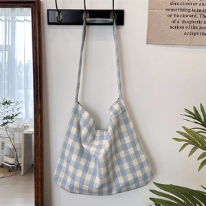 Detail of blue and white checkered canvas shoulder bag hanging in a minimalist room