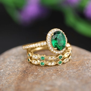 Macro detail of emerald oval halo ring set with gold band on natural stone texture