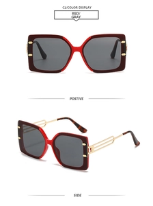 Detail of red square oversized sunglasses featuring golden hollow metal temples and grey lenses