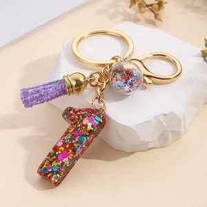 Detail of glittery resin number 1 keychain with colorful star sequins and purple tassel
