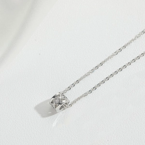 Detailed close-up of a silver quilted cylinder pendant necklace with sparkling zircons