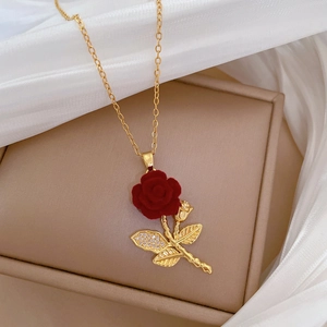 Detail of red rose pendant with gold stem and sparkling crystal leaves on necklace
