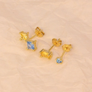 Detailed close-up of S925 sterling silver stamp on gold earrings with blue gemstones