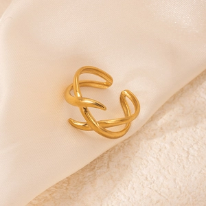 Détail d'une bague croisée en acier titane au fini doré mat sur un socle en pierre chic
