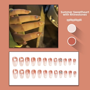 Macro detail of heart press-on nails set with sparkling rhinestones and pink gradient design