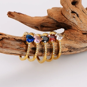 Set of five gold plated heart rings with colorful zircons on natural wood branch