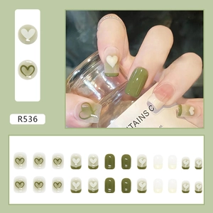Detail van 24 matcha groene en crèmewitte kunstnagels met hartjesontwerpen en French tips