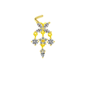 Détail d'un piercing de nez doré avec pendentif fleur, glands en zircone et barre en L