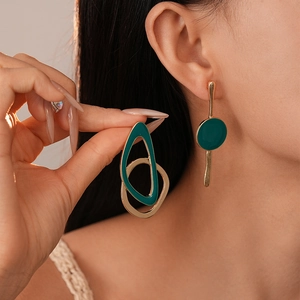 Boucles d'oreilles géométriques asymétriques émaillées or et vert foncé sur modèle