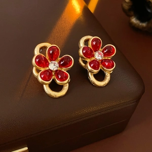 Close-up of vintage gold earrings with red glass flower petals and clear crystals