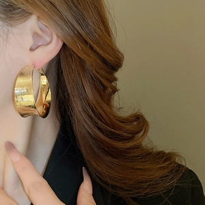 Detailed view of large golden hoop earrings with a brushed textured finish on model