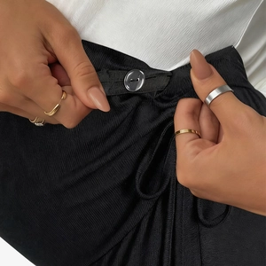 Detail shot of maternity trousers showing adjustable button closure and knit fabric texture