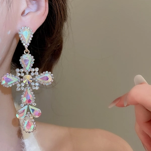 Close-up of rainbow crystal cross earrings with AB rhinestones on a female model