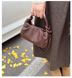 Détail d'un sac à main plissé marron foncé avec poignée nouée dans un décor d'automne