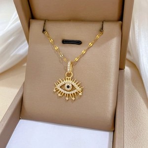 Detail of gold evil eye necklace with zircon stones on silk fabric in jewelry box