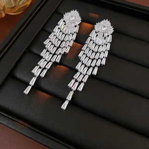Close-up of elegant long silver tassel earrings with sparkling zircon stones on black stand