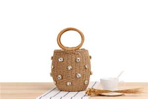 Detail of woven straw bucket bag with rhinestone accents on a summer picnic setting
