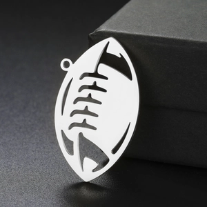 Macro detail of silver stainless steel American football pendant with hollow engraving