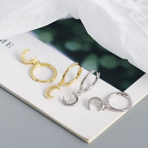 Macro detail of crescent moon earrings in gold and silver with micro-pave zircons