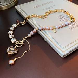Detail of heart pendant necklace with pink pearls and crystals on a vintage book