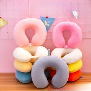 Detailed close-up of colorful plush neck pillows with button closures and hanging loops