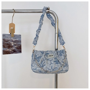Close-up of light blue pleated hobo bag with a decorative metal floral chain detail