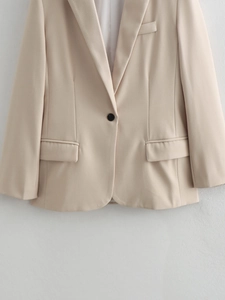 Close-up of beige blazer featuring a notched lapel and a single-button closure