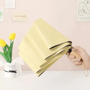 Compact light yellow folding umbrella with natural wooden handle for sun and rain