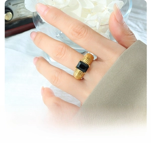 Close-up of titanium steel gold ring with large black rectangular stone on finger