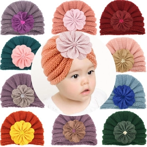 Macro shot of colorful baby knitted turban hats with large flower detail and soft texture
