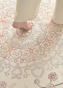 Close-up of soft beige French vintage rug with floral patterns and foot showing texture