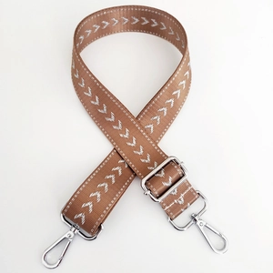 Detail of brown nylon strap with white arrow embroidery and silver metal buckles