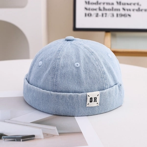 Detailed view of light blue denim docker cap with retro six-panel design and side woven label