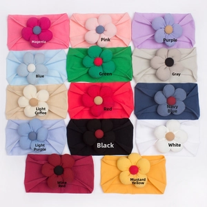 Flat lay of 14 colorful nylon baby flower headbands showing soft knit fabric and texture