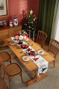 Macro detail of Christmas table runner with printed trees on a wooden holiday dining setup
