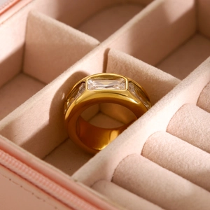 Close-up of a wide gold titanium ring with a rectangular zircon set in a velvet jewelry box